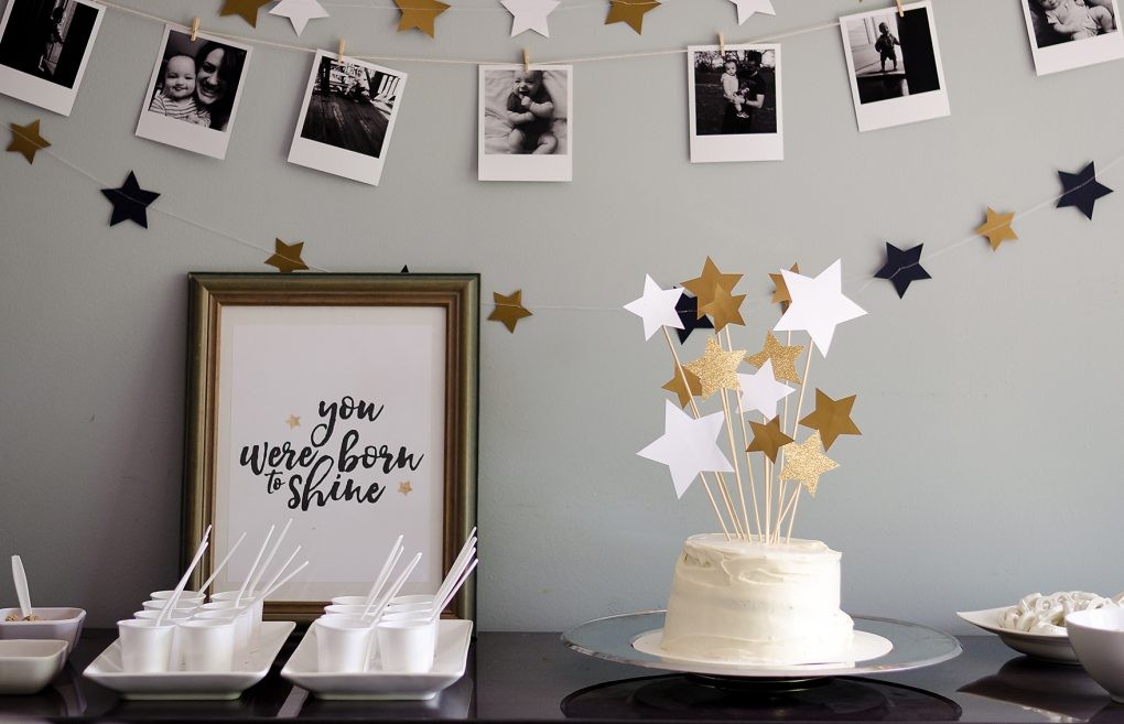 A close-up of the cake table showing the cake and the poster that says "you were born to shine" along with the little plastic cups of pudding