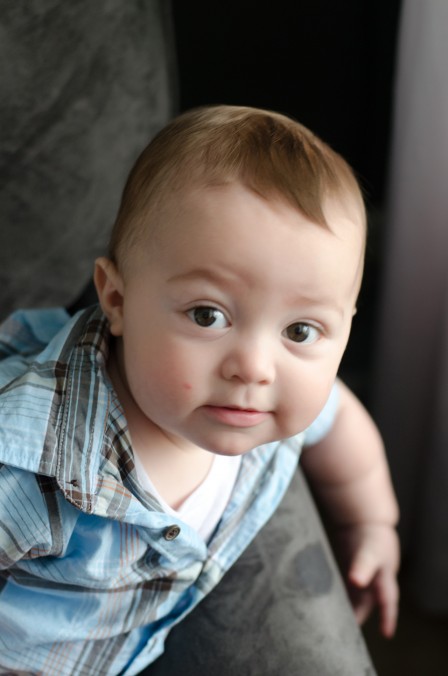 Miles - 9 Month baby photos - On his grey chair looking up at me with his eyebrows raised