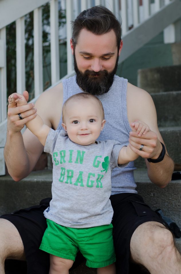 Finn standing in front of Steven, smiling with excitement while daddy holds his hands and looks down at him.