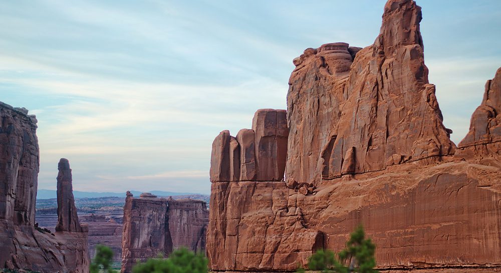 Wide landscape view of the first lookout at Arches national park at sunset. Facing west, towering rock formations glowing red.