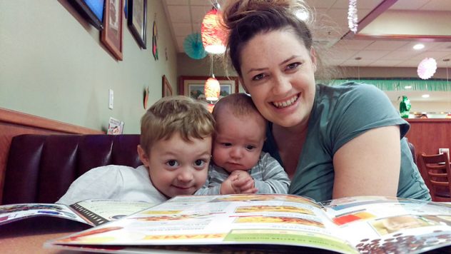 Miles, Finn, and Mom looking at the camera while sitting in the bench at the table for breakfast at Terrible's Casino