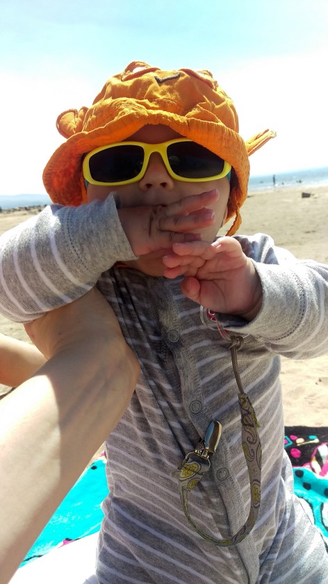 Finn in his hat and glasses, chewing on his hand at the lake