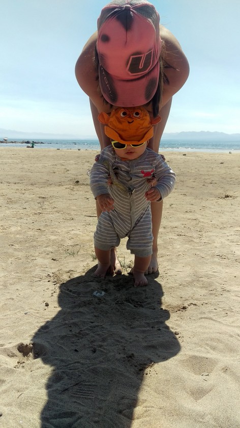 Brooke holding Finn while he feels the sand