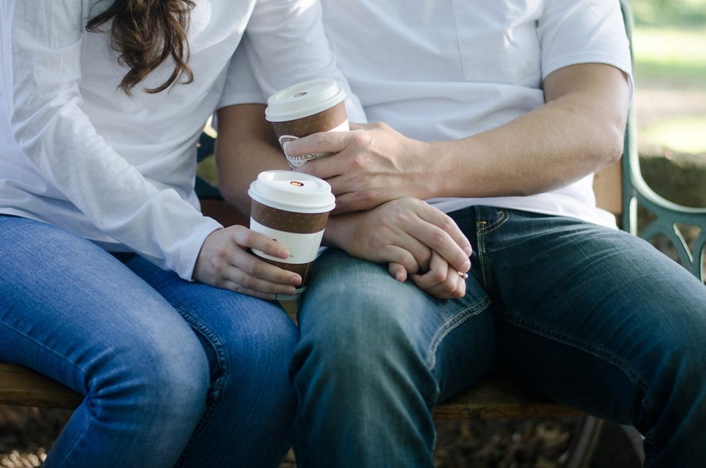 Closeup while holding their coffees and each other's hands